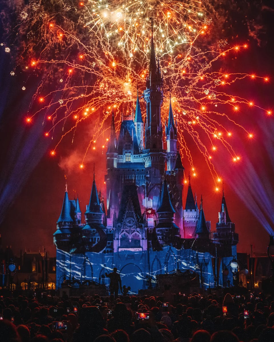 A stunning night view of fireworks illuminating a famous castle, attracting a crowd of tourists.